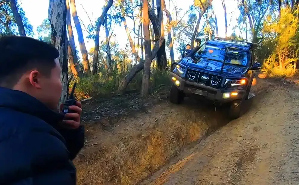 an using a walkie-talkie to coordinate with a 4WD vehicle on an off-road trail.